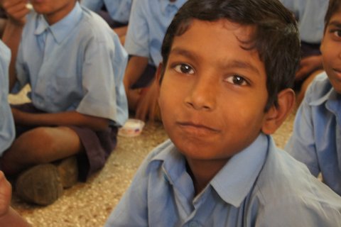 Indien: sitzender Junge blickt in Kamera
