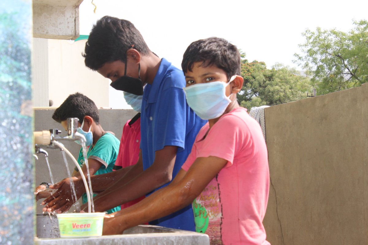 Indien: Haendewaschender Junge mit Schutzmaske